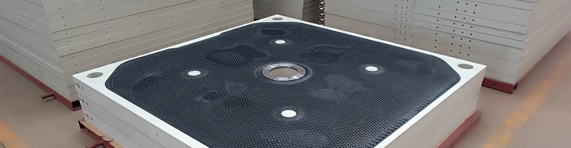Large rubber membrane filter plate and finished filter plate stacks in a production workshop